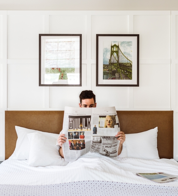 A man reading the paper in bed in his suite at the Heathman Hotel in Portland, Oregon.