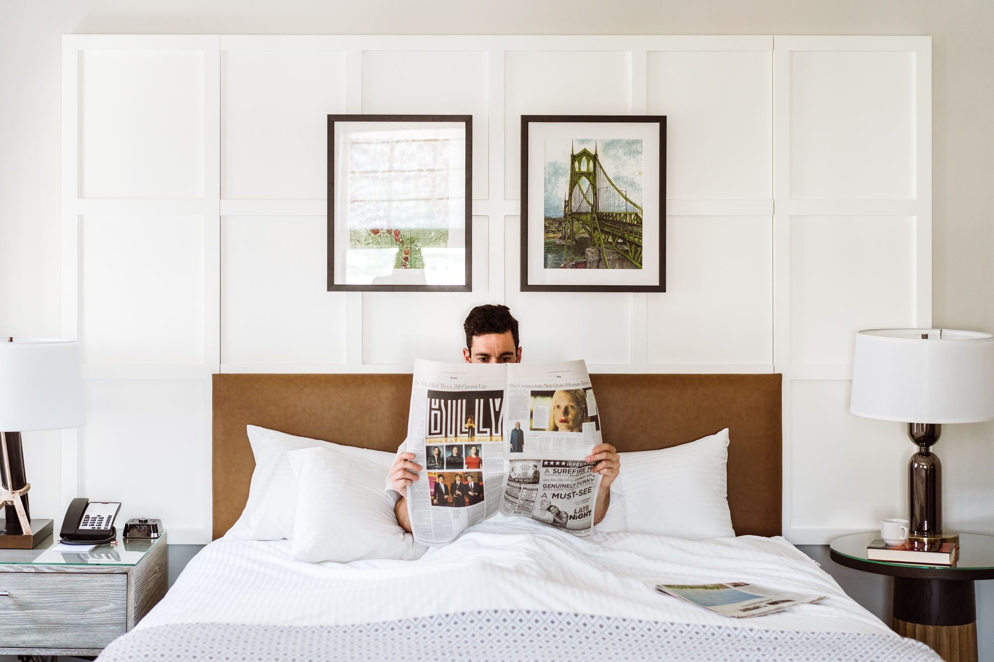 A man reading the paper in bed in his suite at the Heathman Hotel in Portland, Oregon.