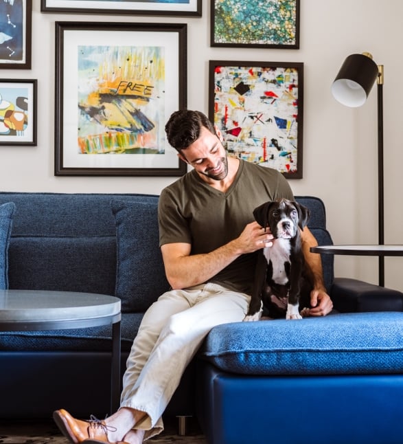 A man on a couch petting a dog.