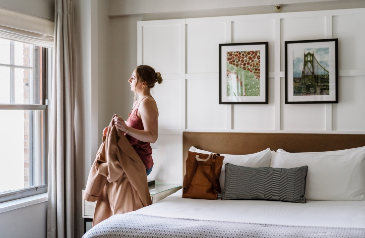 A woman looking out the window of her suite at the Heathman Hotel in Portland, Oregon.