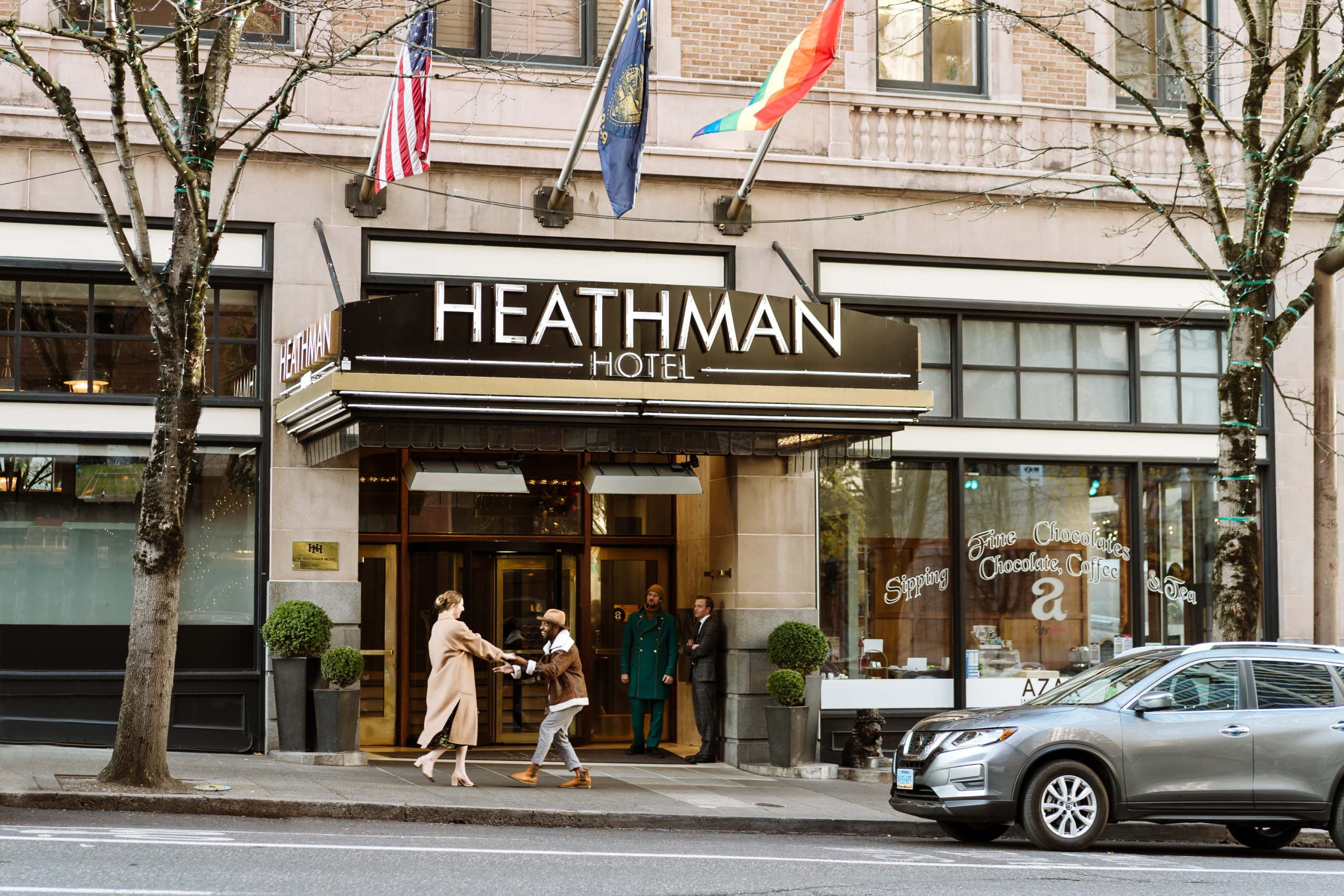 A couple holding hands in front of the Heathman Hotel in Portland, Oregon.