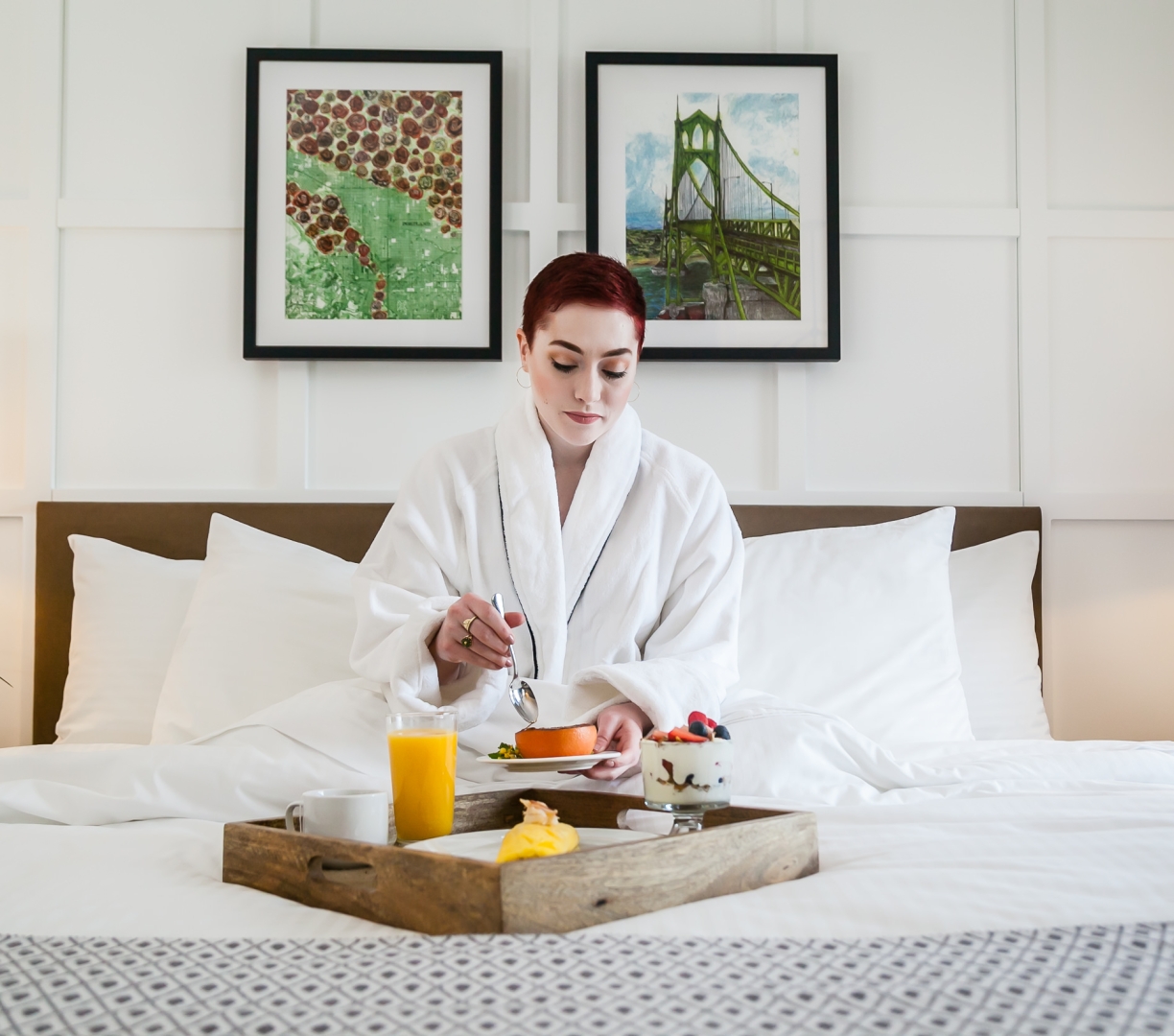 A woman having breakfast in bed in her hotel room at the Heathman Hotel in Portland, Oregon.