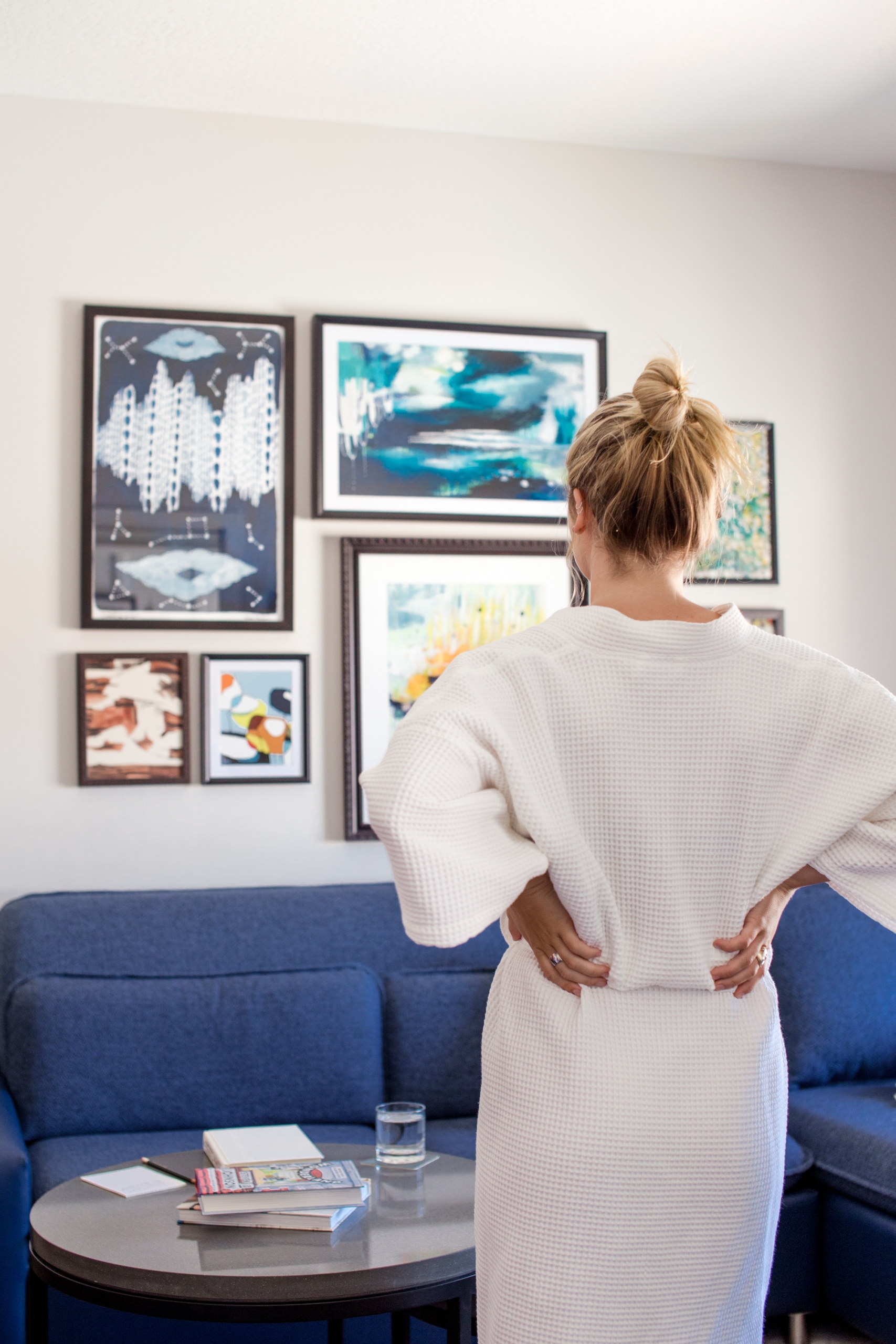 A woman looking at art on the wall of her hotel room.