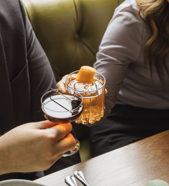 Two people toasting with cocktails.