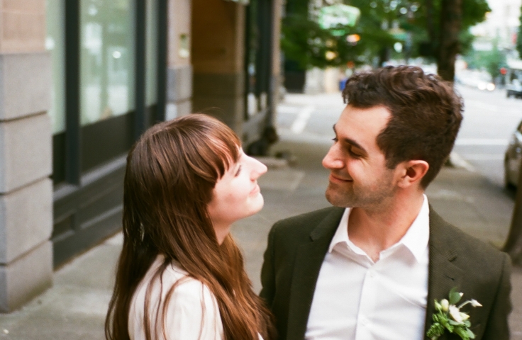 A bride and groom smiling at each other in front of the Heathman Hotel in Portland, Oregon.