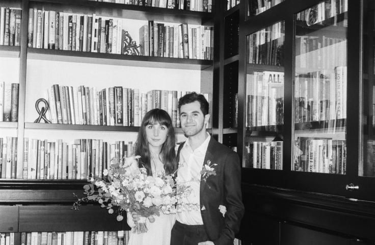 A bride and groom posing in front of the shelves of the Heathman Hotel's library.