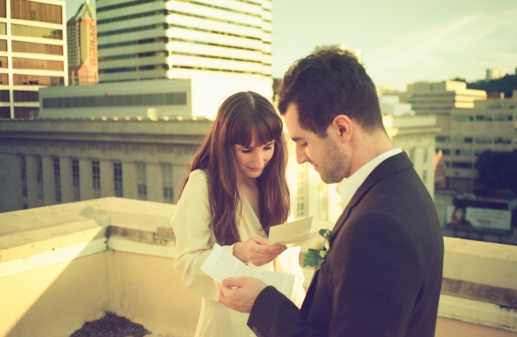 A bride and groom reading letters on a rooftop in Portland, Oregon.